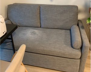 Love seat upholstery with blood stain and baking soda residue before professional cleaning in Kelowna